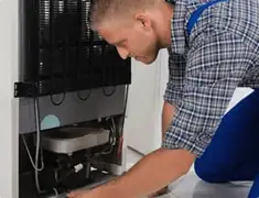 Refrigerator repair technician servicing the compressor and condenser area in Nashville, TN