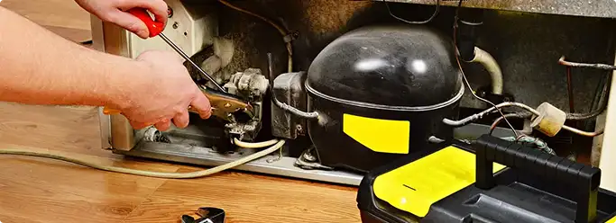 Refrigerator repair technician fixing the compressor and wiring in Nashville, TN